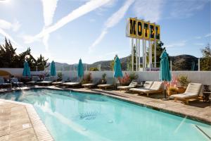 una piscina en un hotel con sillas y sombrillas en Skyview Los Alamos - 21 & Over Pool en Los Álamos