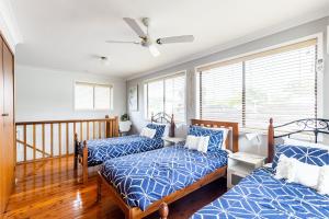 two beds in a room with two windows at Willows At The Bay Large House with Aircon WI-FI and Boat Parking in Shoal Bay
