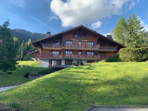 uma grande casa de madeira numa colina relvada em Route de la Résidence em Villars-sur-Ollon