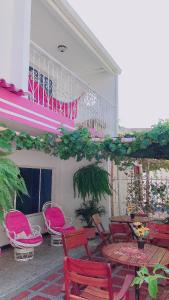 patio con mesas y sillas rosas y balcón en Casa Hospedaje Villaluz- a 5 minutos de la Playa, en Santa Marta