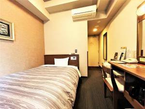 福岡市にあるホテルルートイン博多駅前-博多口-のベッドとデスクが備わるホテルルームです。