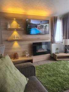 sala de estar con chimenea y TV de pantalla plana en Beautiful 2 bedroom caravan, holiday park Tenby, en Pembrokeshire