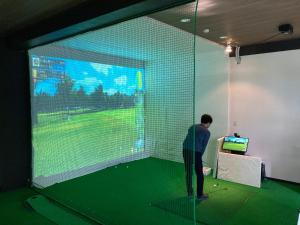 a man is playing a video game on a screen at 趣味複合施設イイトコ 