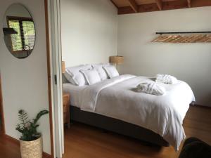 1 dormitorio con 1 cama con sábanas blancas y espejo en Adrift In Golden Bay- Absolute Beachfront Villas, en Collingwood