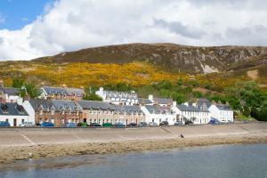 a row of buildings on a beach next to the water at Ullapool Youth Hostel in Ullapool