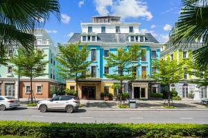 a blue and yellow building with cars parked in front of it at The Enchanted Hotel in Ha Long