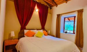 a bedroom with a bed with red curtains and a window at Casa de Ollanta ByB in Ollantaytambo