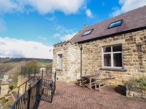 a stone house with a picnic table on a brick patio at Limber View in Grosmont