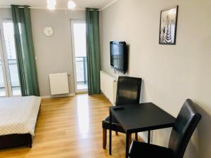 een woonkamer met een tafel en een tv aan de muur bij Holdek Apartamenty Ceglana in Katowice