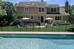 une maison avec une clôture à côté d'une piscine dans l'établissement Hamptons Hideaway, à Hampton Bays