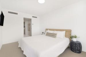 ein weißes Schlafzimmer mit einem großen Bett mit weißer Bettwäsche in der Unterkunft Kirra Gardens Unit 27 in Gold Coast