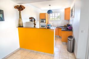 a kitchen with orange and white cabinets and a yellow island at BED AND COFFEE PLAGE in La Trinité