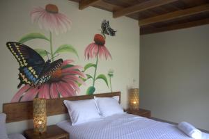 1 dormitorio con 1 cama con una pintura de mariposa en la pared en Villa Amanda Resort, en Mazatenango