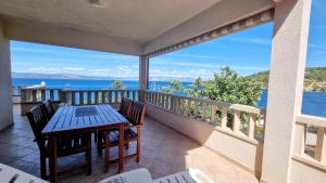 a balcony with a table and chairs and a view of the ocean at Apartments Mlad - with pool in Rogač