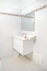 Baño blanco con lavabo y espejo en Suite jacuzzi et vue panoramique - BED AND COFFEE AIRPORT en Ducos