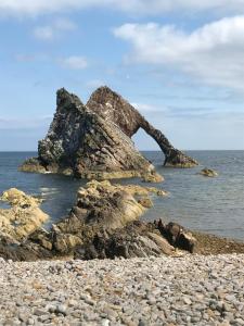 een grote rots in het water op een strand bij Melody Brooks Caravan Park in Portknockie