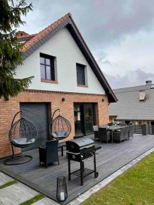 una terraza con sillas, una parrilla y una casa en MazuryDreamHouse, en Pelnik