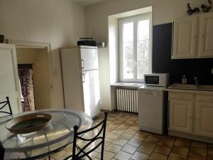 a kitchen with a table and a white refrigerator at Gîte indépendant au bord de la rivière, cadre historique, pêche, animaux bienvenus, parking privé - FR-1-586-22 in Mareuil-sur-Arnon