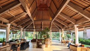 a large building with wooden ceilings and tables and chairs at Ayurvedagram Bali in Ubud