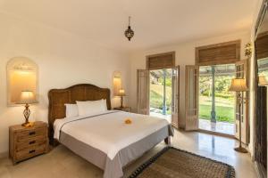Schlafzimmer mit einem großen weißen Bett und Glasschiebetüren in der Unterkunft 5bd Moroccan style luxury Villa in the heart of Canggu in Canggu
