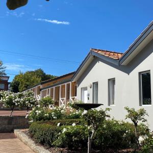 a white house with bushes and flowers at Higgins Lane Motel in Margaret River Town