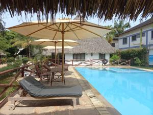 uma piscina com guarda-sol, cadeiras e mesa e uma piscina em New Muna House. em Ukunda