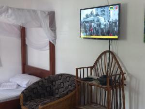 um quarto com uma cama e uma TV na parede em New Muna House. em Ukunda