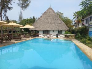 uma grande piscina azul com um edifício de palha em New Muna House. em Ukunda