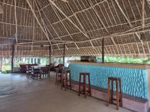 um restaurante com mesas e cadeiras sob um telhado de palha em New Muna House. em Ukunda