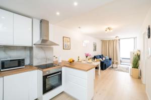 a kitchen with white cabinets and a living room at Apartment NAVA - new and spacious gem - FREE PARKING in Dubrovnik