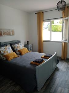 Un dormitorio con una cama con almohadas amarillas y una ventana en L escapade, en Rabastens