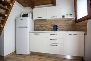 una cucina con armadietti bianchi e frigorifero di Cortile Antico a Trapani