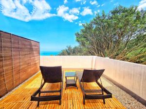 dos sillas en una terraza con el océano en el fondo en A Promised Land BnB, en Jiufen