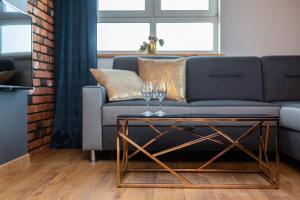 a living room with a couch and two wine glasses on a table at Apartments Parks of Warsaw by Renters in Warsaw