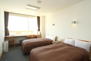 Spa SHIOSAI في Toyoura: غرفة فندقية بسريرين ونافذة