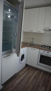 cocina con armarios blancos, fregadero y lavavajillas en Central Apartament, en Klaipėda