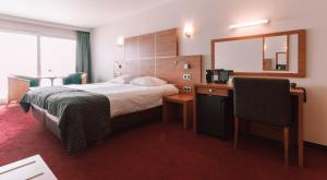 a hotel room with a bed and a desk and a mirror at Hotel Riant-Séjour by WP Hotels in Blankenberge