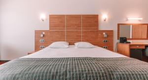 a bedroom with a large bed with a wooden headboard at Hotel Riant-Séjour by WP Hotels in Blankenberge