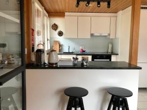 a kitchen with white cabinets and black counter stools at Chalet Pironnet with BEST Views, Charm and Comfort! in Lauterbrunnen