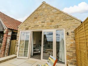 an extension to a stone cottage with sliding glass doors at Shippon in York