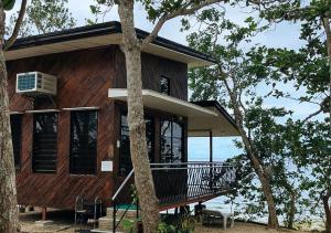 a wooden house with a balcony in the trees at Tabique by the sea in Cebu City
