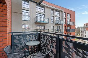 a balcony with chairs and a table and a building at Dwie Motławy Apartinfo Apartments in Gdańsk