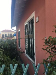 Casa vacanze Villetta San Pietro 9 في ديانو مارينا: مبنى وردي بنوافذ مغطاة خضراء وشجيرات
