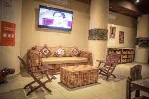 a living room with a couch and chairs and a tv at African Home Hotel in Gaborone