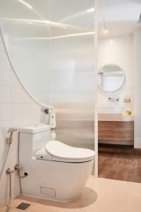 a bathroom with a white toilet and a mirror at Bonsai Hotel Bangkok in Bangkok