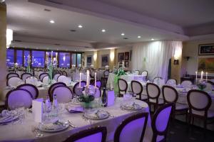チンゴリにあるHotel Tetto delle Marche - Ristorante dei Contiの紫色の照明が施された白いテーブルと椅子が備わる宴会場