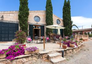 Casa con patio con flores y sombrilla en Es Revellar Art Resort - Adults Only, en Campos