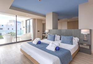a bedroom with a large bed with blue and white pillows at Marins Playa in Cala Millor