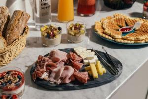 a table with a plate of food with meats and cheese at Amery House in Sliema