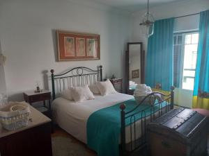 um quarto com uma cama e uma janela com cortinas azuis em Casa da Gó na Ericeira